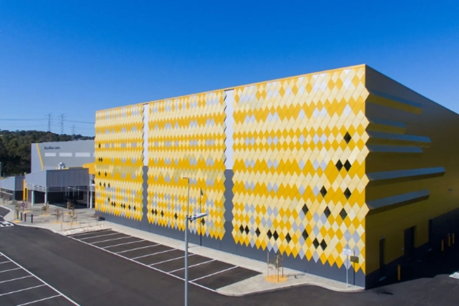 Mullum Mullum Stadium from the car park, its yellow patterned wall in the sun