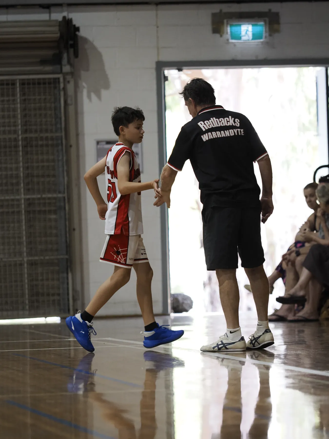 A Redbacks coach high-fiving a player coming off the court