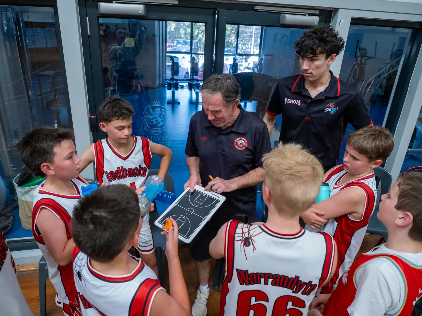 A Redbacks coach drawing up a play on a whiteboard for his team in a timeout